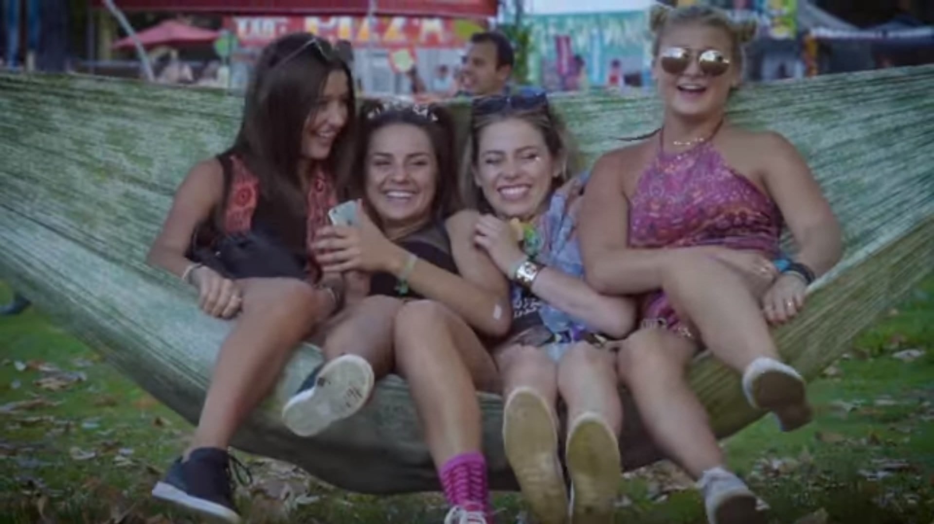 ravers and music festival attendees sitting in hammock at festival