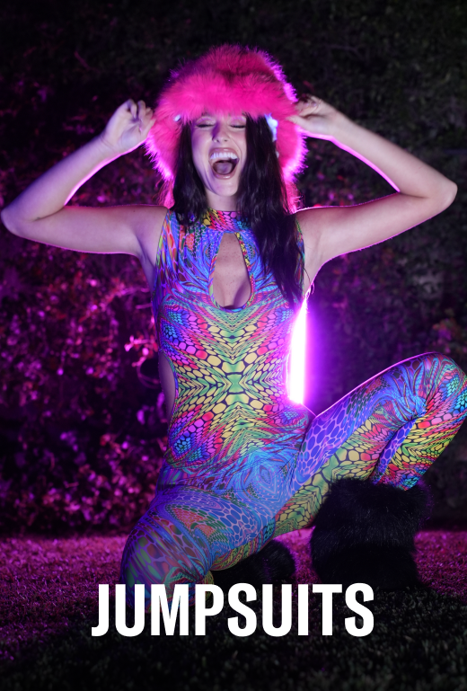 Person wearing a colorful jumpsuit with a pink headpiece against a dark background